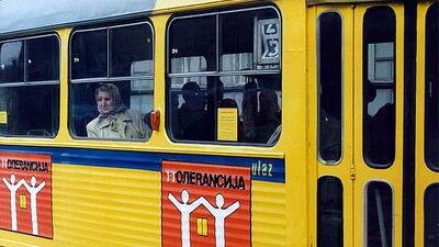 Yellow tram with posters advocating for tolerance, with passengers looking out the windows.