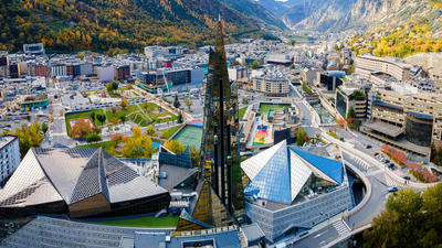 Aerial view of futuristic buildings and mountains in Andorra la Vella, under a clear sky.