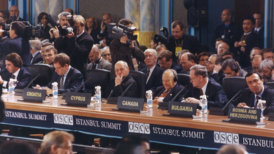 Photo of the OSCE Istanbul Summit, showing diplomats, country representatives, and media capturing the high-level discussions.